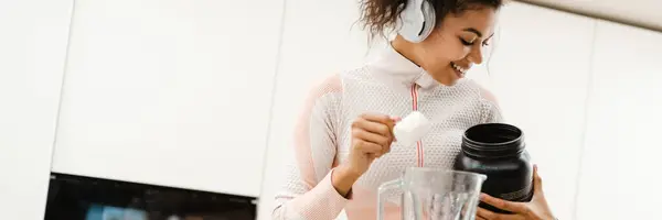 Wanita Hitam Headphone Membuat Smoothie Dengan Protein Rumah — Stok Foto