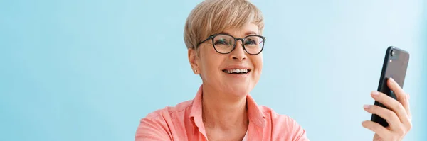 Europeisk Moden Kvinne Briller Som Smiler Bruker Mobiltelefon Isolert Blå – stockfoto