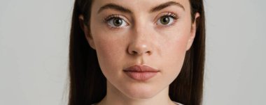 Genç esmer kadın poz veriyor ve beyaz arka planda izole edilmiş kameraya bakıyor.