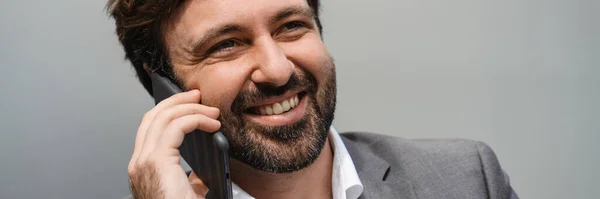Улыбающийся Бизнесмен Средних Лет Разговаривает Мобильному Телефону Фоне Серой Стены — стоковое фото