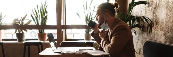 Joven Hombre Blanco Mascarilla Usando Ordenador Portátil Mientras Bebe Café — Foto de Stock