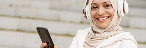 Sorridente Donna Musulmana Mezza Età Cuffie Che Tiene Telefono Cellulare — Foto Stock