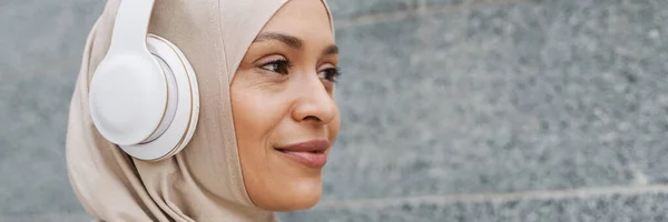 Lähi Idän Nainen Hijabissa Kuuntelemassa Musiikkia Langattomilla Kuulokkeilla Ulkona — kuvapankkivalokuva