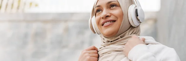 Lähi Idän Nainen Hijabissa Hymyilee Kuunnellessaan Musiikkia Langattomilla Kuulokkeilla Ulkona — kuvapankkivalokuva