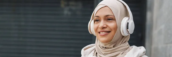 Perempuan Timur Tengah Tersenyum Sambil Mendengarkan Musik Dengan Headphone Nirkabel — Stok Foto