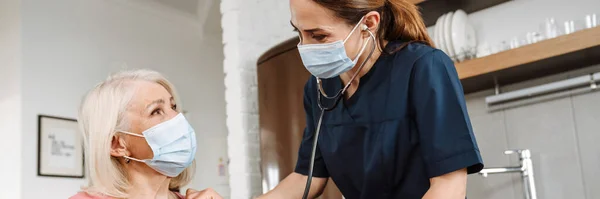 Seorang Dokter Wanita Dengan Topeng Pelindung Sekali Pakai Mendengarkan Stetoskop — Stok Foto