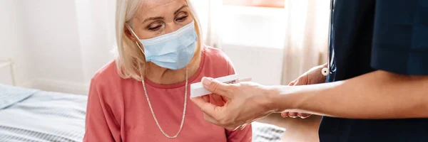Eine Ärztin Zeigt Ihrem Älteren Patienten Mit Schutzmaske Hellen Raum lizenzfreie Stockfotos