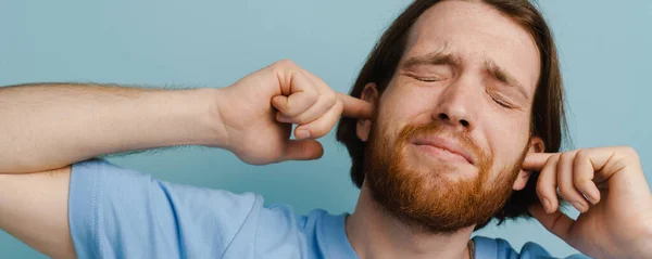Junger Mann Mit Bart Steckt Sich Die Ohren Während Isoliert Stockbild