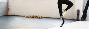 Evde yoga yaparken protez takan genç bir kadın.