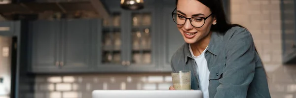 Valkoinen Hymyilevä Nainen Juo Smoothie Työskennellessään Kannettavan Tietokoneen Kotona Keittiö — kuvapankkivalokuva