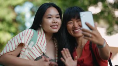 Yazın dışarıda cep telefonuyla konuşan iki tatlı Asyalı kadın. 