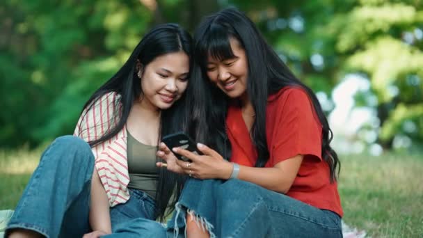 Dua Wanita Asia Tertawa Melihat Ponsel Dan Berbicara Sambil Duduk — Stok Video