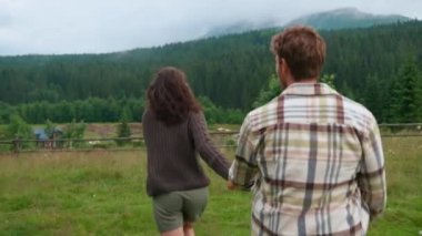 Dağa koşup el ele tutuşan neşeli çiftin arka manzarası