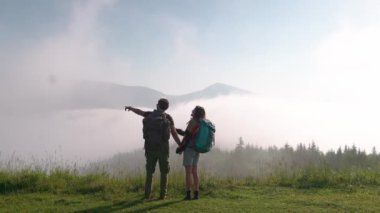 Sırt çantalarıyla dağda yürüyüş yapan ve sisi gören sevimli bir çift. Kamp kavramı