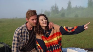 Güzel bir çift konuşuyor ve bir sisin içinde dağdaki ağaç kütüğünde otururken manzarayı işaret ediyor. Kamp kavramı