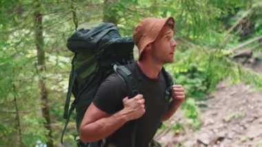 Panama şapkalı mutlu sarışın adam sırt çantasıyla dağlarda yürüyüş yapıyor.