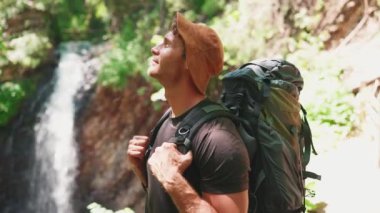 Panama şapkalı sarışın turist dağlardaki şelaleye bakıyor.