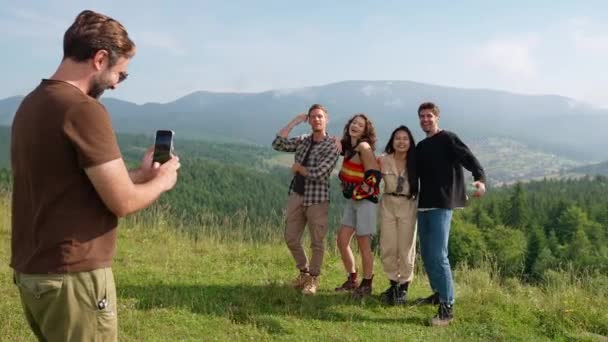 남자는 산에서 자신의 쾌활한 다국적 친구의 전화에 사진을 찍습니다 — 비디오