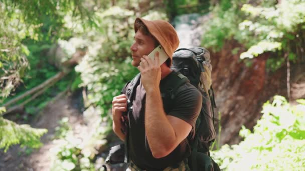 Panama Şapkalı Tatlı Sarışın Adam Telefonda Dağlarda Şelaleye Karşı Konuşuyor — Stok video