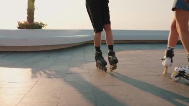 Çift gün batımında deniz kenarında paten kayıyor.