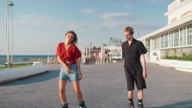 Deniz kenarında paten kayarken dans eden mutlu genç çift