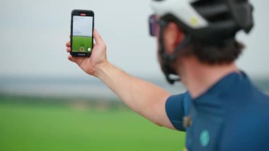 Sporcu adam bisiklete bindikten sonra doğanın videosunu cep telefonuyla kaydediyor.