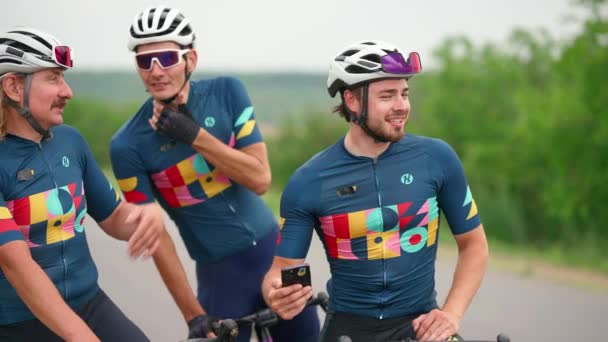 Три Усміхнені Спортсмени Велосипедисти Розмовляють Дивляться Телефону Після Їзди Велосипеді — стокове відео