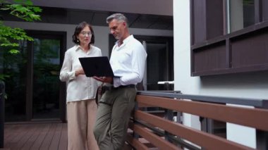 Kendine güvenen olgun meslektaşlar iş yemeği için teras kafeteryasında laptopta iş konuşuyorlar.