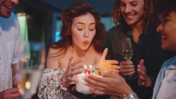 微笑的生日女孩一边在餐厅的阳台上和朋友们一起庆祝 一边吹灭蛋糕上的蜡烛 — 图库视频影像