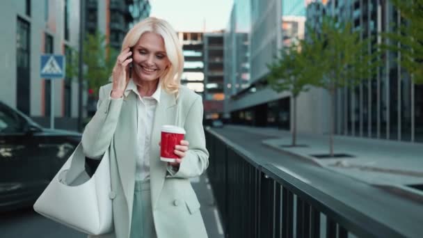 滑稽的金发女商人穿着西服 一边打电话一边在外面喝咖啡 — 图库视频影像