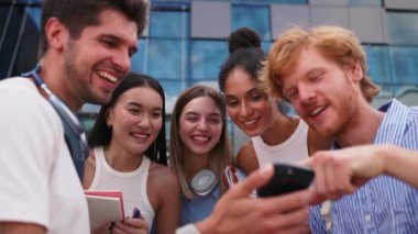 Çok uluslu genç öğrencilerin konuşmalarına ve cep telefonlarına gülerek yaz mevsiminde üniversitenin yakınında daireler çizip duruyorlar.