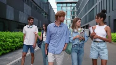 Yazın üniversitenin yanında konuşan ve yürüyen çok kültürlü çok kültürlü genç öğrenciler.