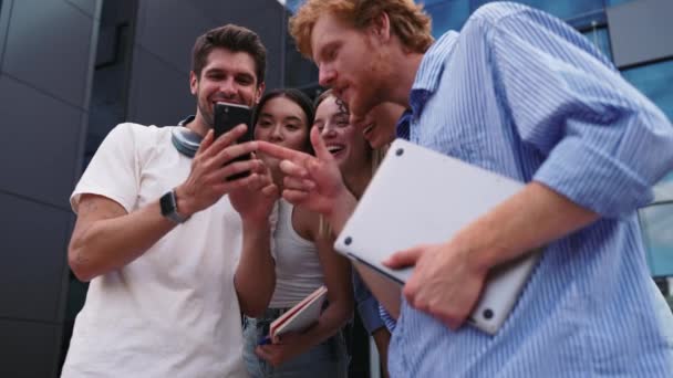 Смешные Многонациональные Молодые Студенты Разговаривают Смотрят Мобильный Телефон Стоя Кругу — стоковое видео
