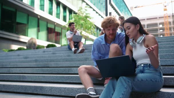 Jovens Estudantes Multiculturais Surpresos Digitando Laptops Sentados Escadas — Vídeo de Stock