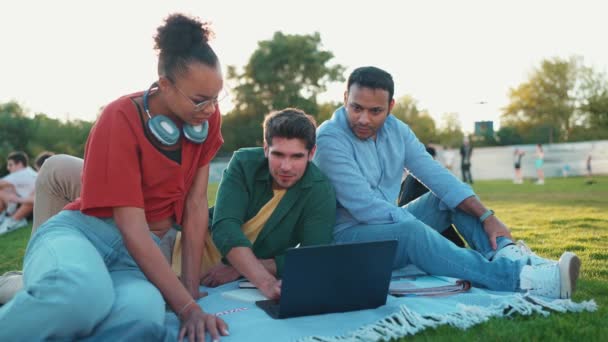 Wesoły Wielorasowych Studentów Rozmowy Pisania Laptopie Siedząc Kocu Trawie Świeżym — Wideo stockowe