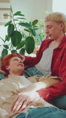 Evdeki kanepede konuşan boyalı saçlı sevimli eşcinsel çiftin yan görüntüsü.