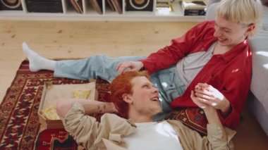 Saçları boyalı, konuşan ve evde el ele tutuşan sevimli eşcinsel çiftin yan görüntüsü.