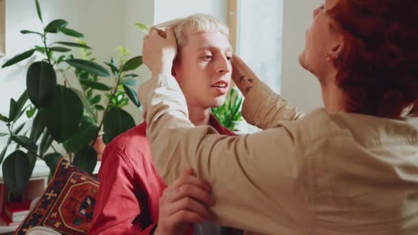 可爱的一对年轻的同性恋夫妇 在家里的沙发上把头发染成了拥抱和固定的样子 — 图库视频影像
