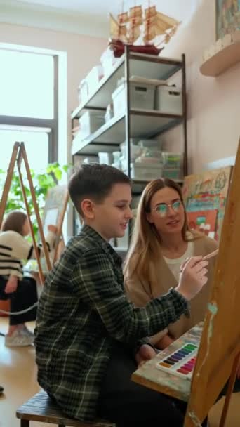 Leende Lärare Tittar Barn Måla Och Prata Med Pojke Konstskola — Stockvideo