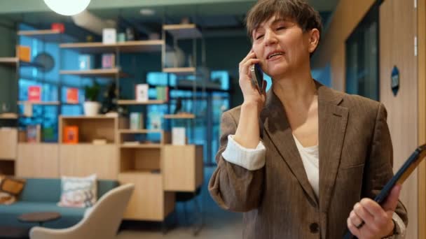 Glad Ældre Brunette Kvinde Taler Telefon Mens Går Med Papirer – Stock-video