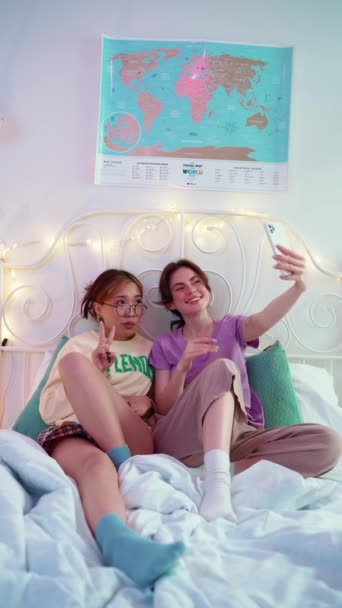 Två Vackra Multikulturella Kvinnliga Vänner Tar Selfies Mobilen Sängen Övernattning — Stockvideo