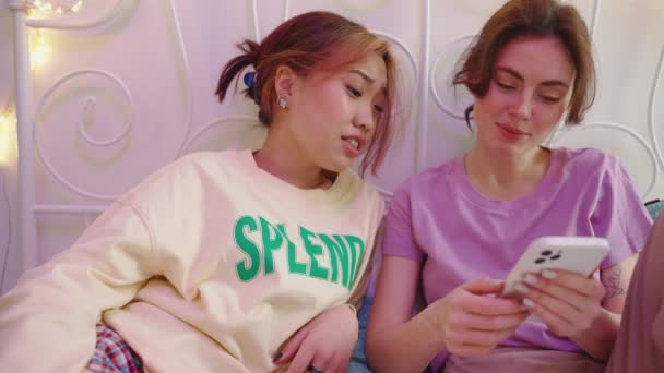 Дві Щасливі Мультикультурні Друзі Дивлячись Мобільний Телефон Розмовляючи Ліжку Сплячому — стокове відео