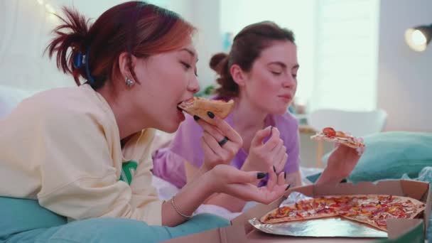 Милые Транснациональные Девушки Разговаривают Едят Пиццу Кровати Время Ночевки — стоковое видео
