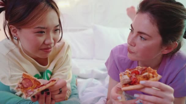 Улыбающиеся Транснациональные Девушки Разговаривают Едят Пиццу Кровати Время Ночевки — стоковое видео