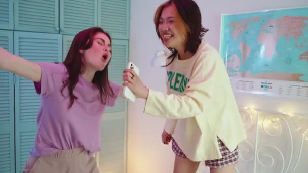 Neşeli Çokuluslu Kızlar Bir Pijama Partisinde Yatakta Şarkı Söyleyip Dans — Stok video