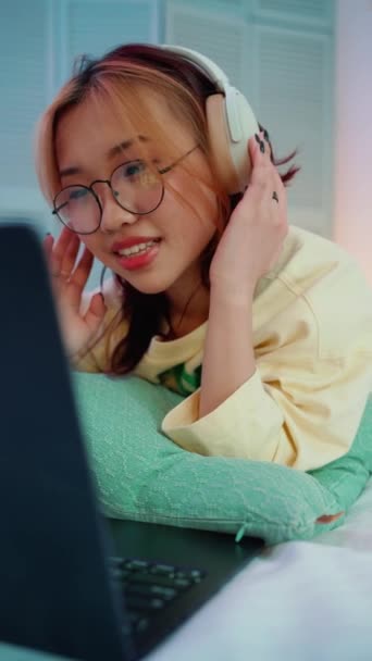 Vicces Fiatal Ázsiai Szemüvegben Videoklipet Néz Laptopon Fejhallgatóval Énekel Ágyon — Stock videók