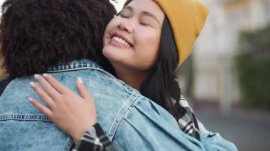 İki çok kültürlü kız öğrencinin sokakta buluştuklarında kucaklaşmaları.