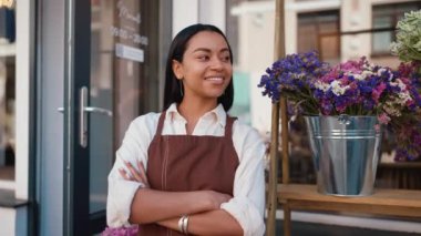 Cheerful african waitress in apron welcoming guests at door of cafe