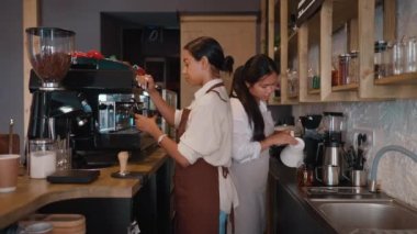 Side view of happy multicultural waitresses brewing coffee at cafe