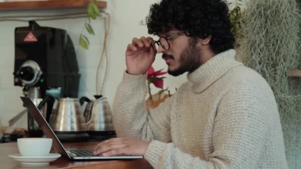 Happy Curly Haired Indian Man Beige Sweater Working Laptop Cafe — Vídeo de Stock